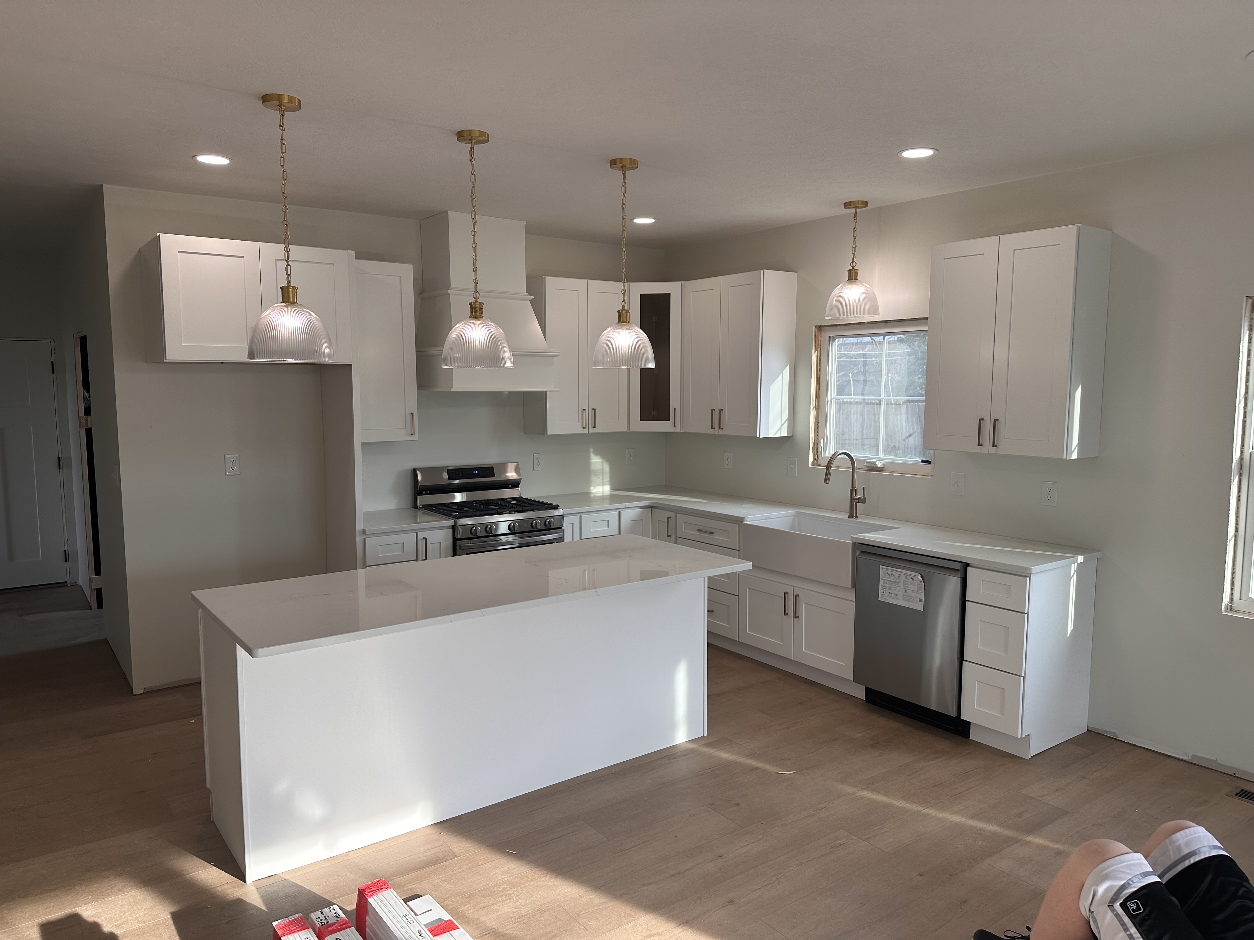 Home #9 kitchen under construction, white cabinetry with brass pendant lighting